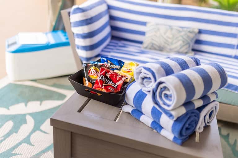 Rolled blue and white striped towels with snacks on poolside table