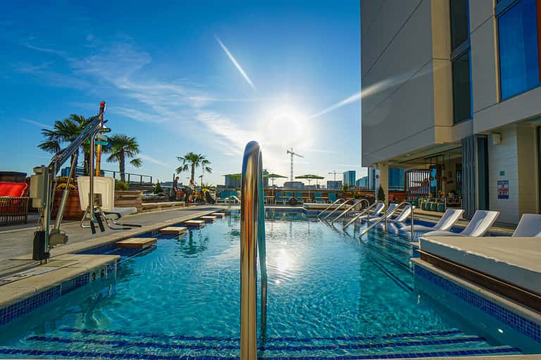 Contemporary outdoor pool with blue water, loungers, palm trees, and modern building architecture
