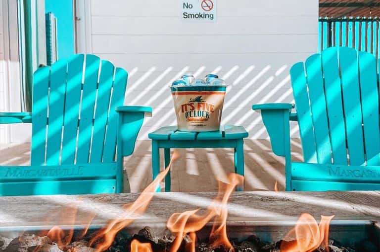 Turquoise Adirondack chairs facing a fire pit with a beverage bucket on a small table