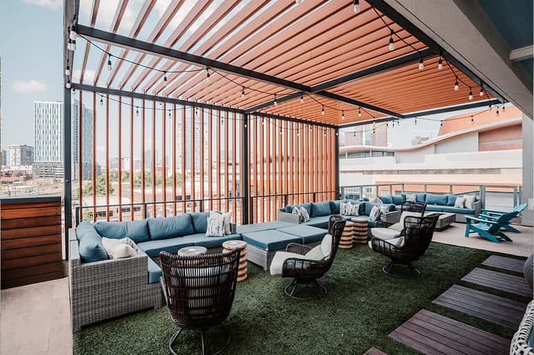 Rooftop lounge with retractable orange pergola, sectional seating, and city skyline views