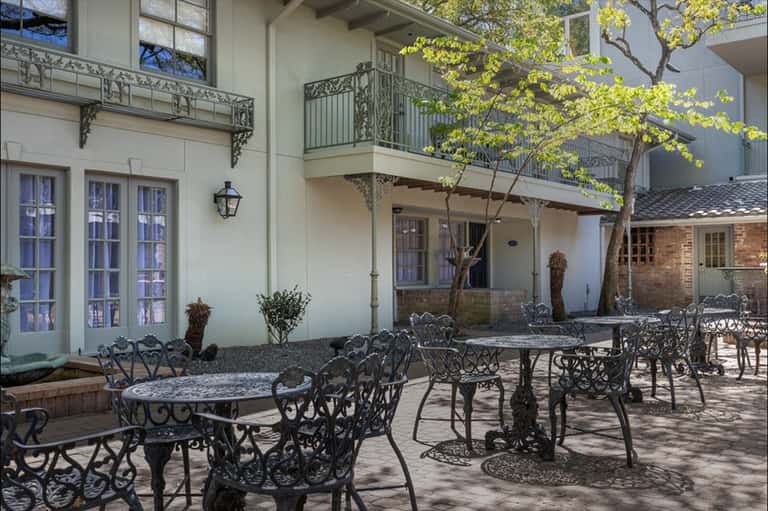 Ornate courtyard with wrought iron furniture and tables, colonial-style architecture with brick pathways