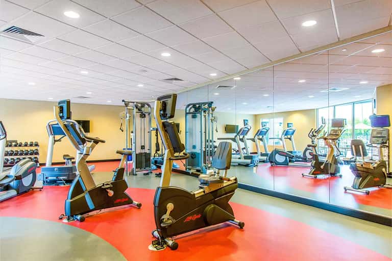Fitness center with colorful floor, exercise bikes, weight equipment, and full-length mirror