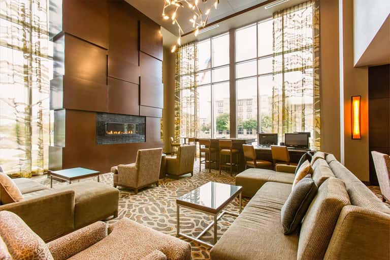 Contemporary lobby with fireplace, high ceilings, gold accents, and elegant furnishings