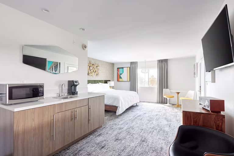 Spacious hotel suite with kitchenette, king bed, sitting area, and modern furnishings