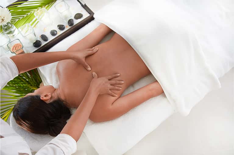 Woman receiving hot stone massage treatment at spa with calm, serene setting