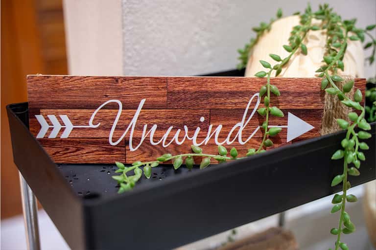 Wayfinding sign reading 'Alfresco' with arrow on wooden planter with cascading greenery