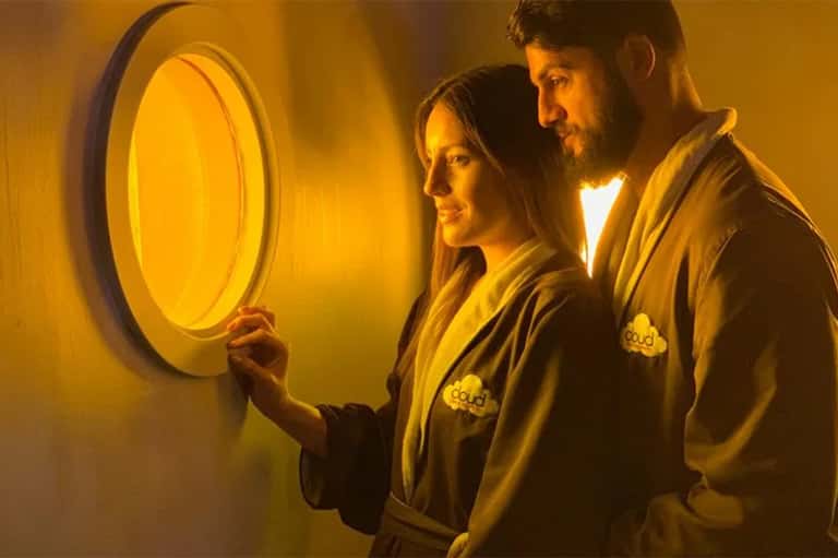 Two people in yellow spa robes examining illuminated circular wellness feature
