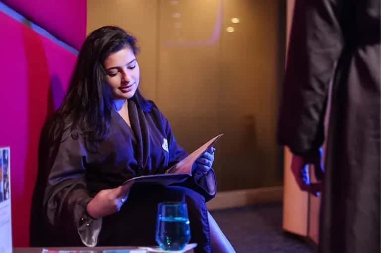 Female hotel staff member in dark blazer reviewing documents in modern lounge area