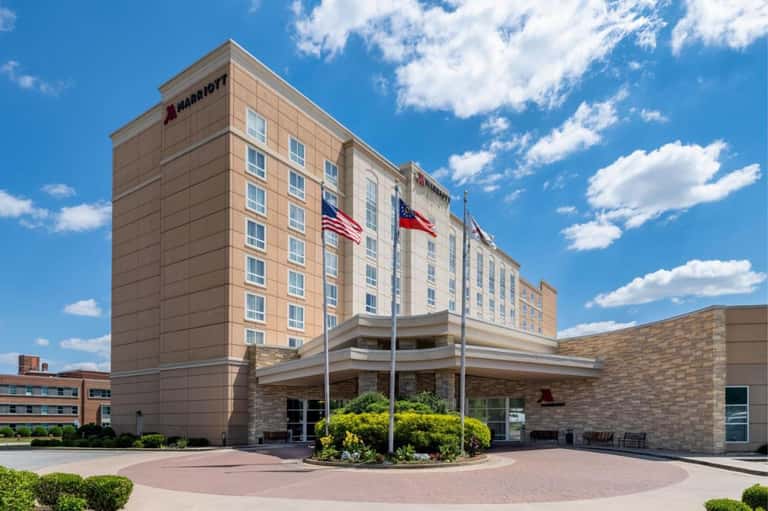 Marriott hotel exterior with brick facade, entrance, flags, and manicured landscaping