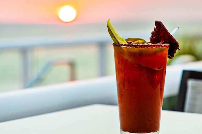 Sunset cocktail with lime garnish and dark red drink by ocean view at beachfront resort