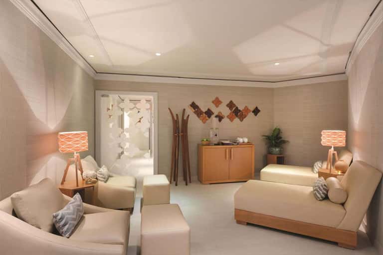 Spa relaxation room with cream seating, wooden accents, and warm ambient lighting