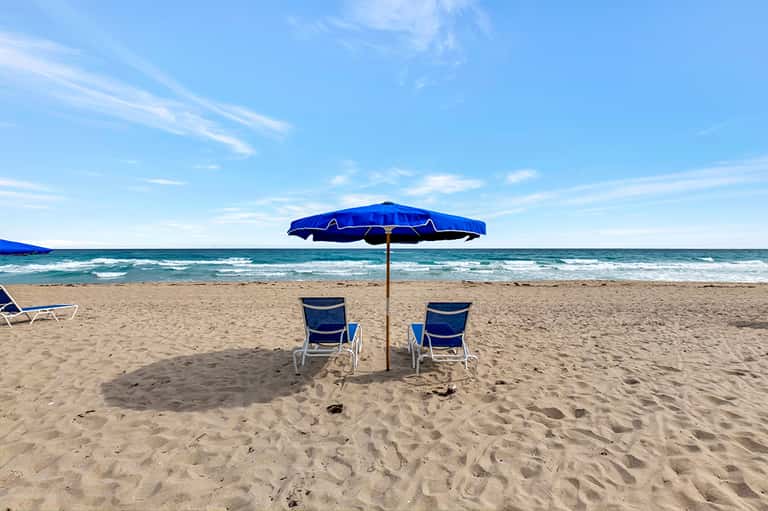 Beach chairs with blue umbrella on sandy beach overlooking the Atlantic Ocean