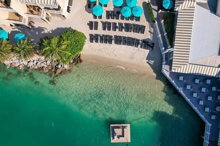 Aerial view of beachfront resort with turquoise water and lounge chairs