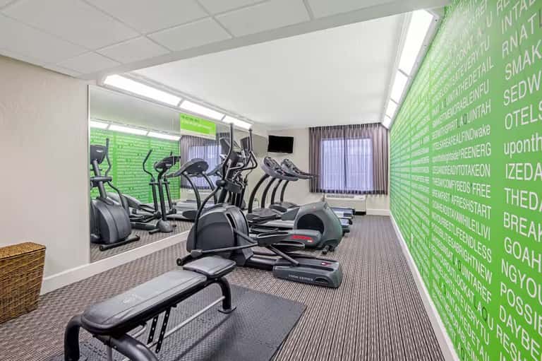 Fitness center with cardio equipment, mirrored walls, bright lighting, and motivational green signage