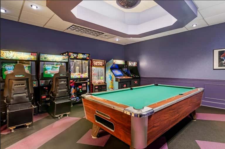 Recreation room with pool table, arcade games, and purple walls with pink accents