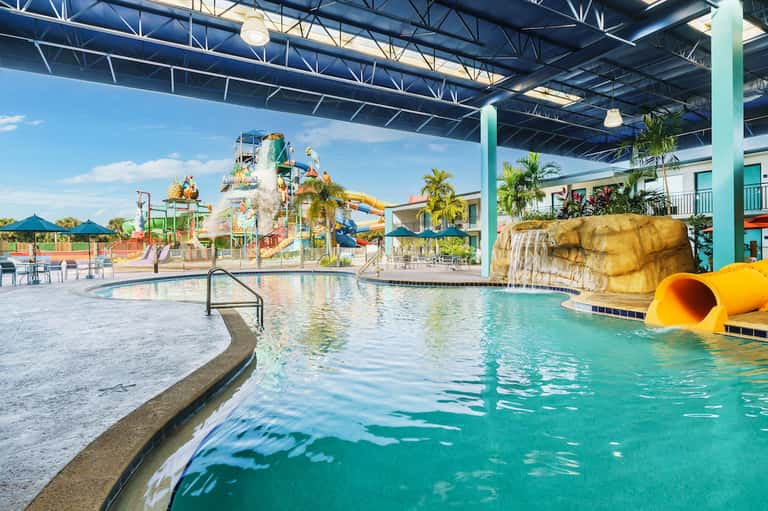 Indoor water park with slides, splash pad, and lazy river under metal roof structure