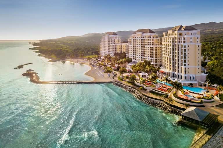 Beachfront resort with multi-story buildings overlooking turquoise ocean and sandy beach
