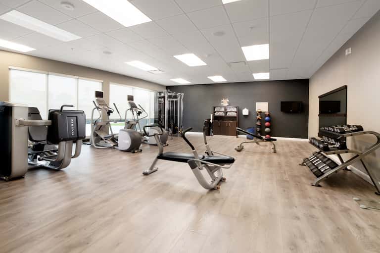 Well-equipped gym with cardio machines, weight equipment, and mirrors