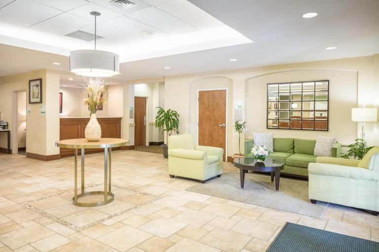Hotel lobby with cream-colored seating, green accent chairs, and modern lighting