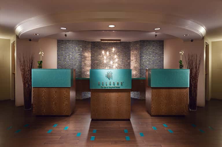 Modern spa reception area with three turquoise and wood check-in desks and decorative brick wall