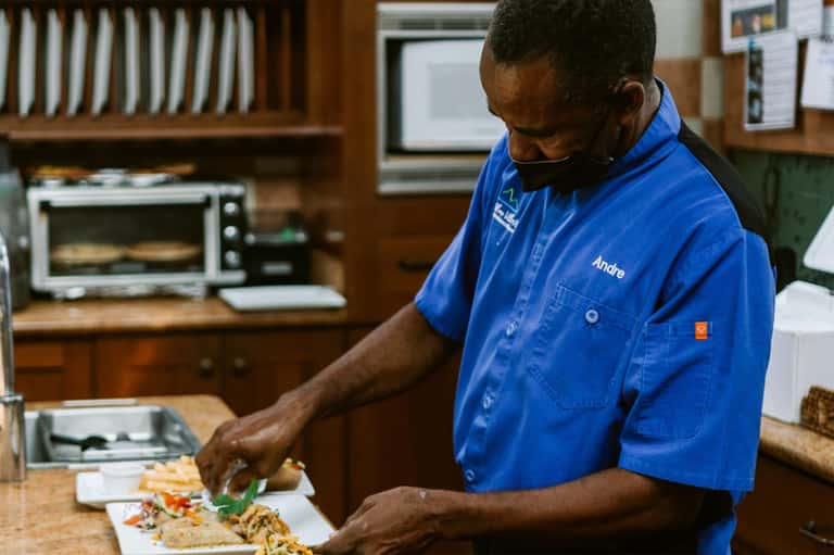 Chef preparing food in a professional kitchen wearing a blue chef's coat