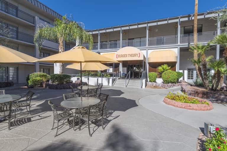 Hotel courtyard with outdoor dining area, umbrella-covered tables, and Burger Theory restaurant