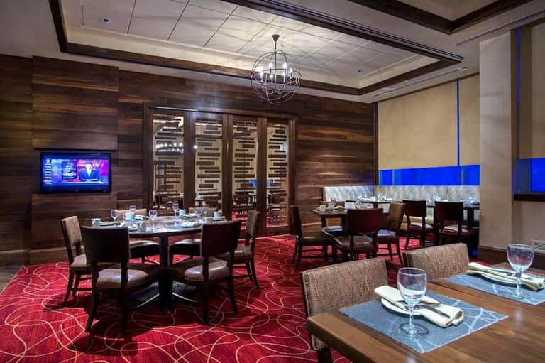 Upscale private dining room with dark wood, wine cellar, red carpet, and round tables