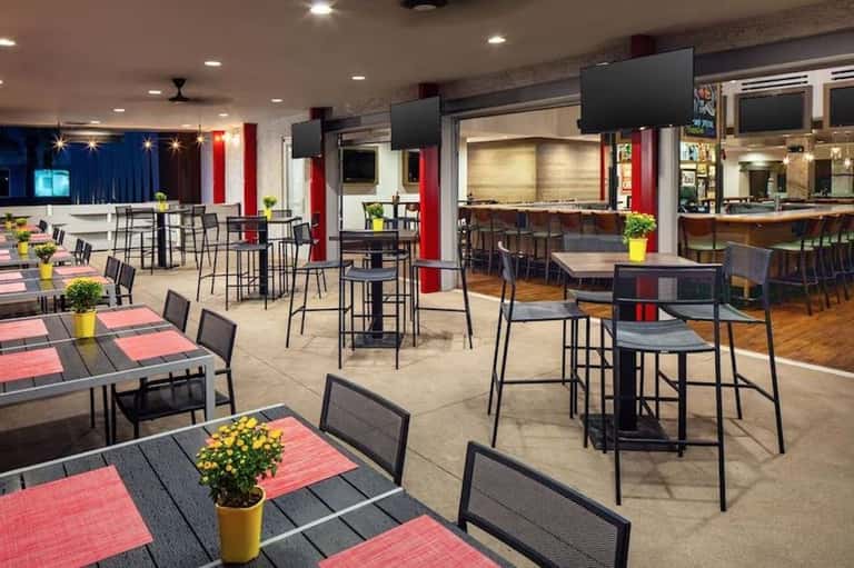 Spacious hotel event space with high ceilings, red and blue accents, and multiple dining areas