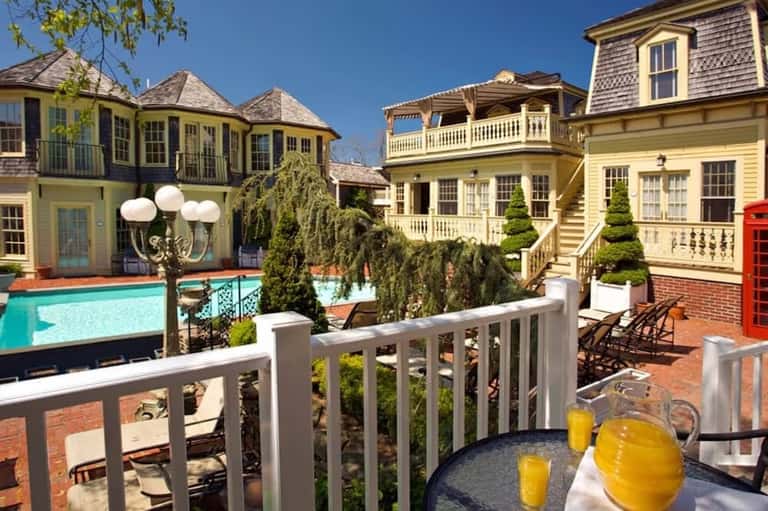 Elegant yellow colonial-style mansion with pool surrounded by manicured gardens and landscaping