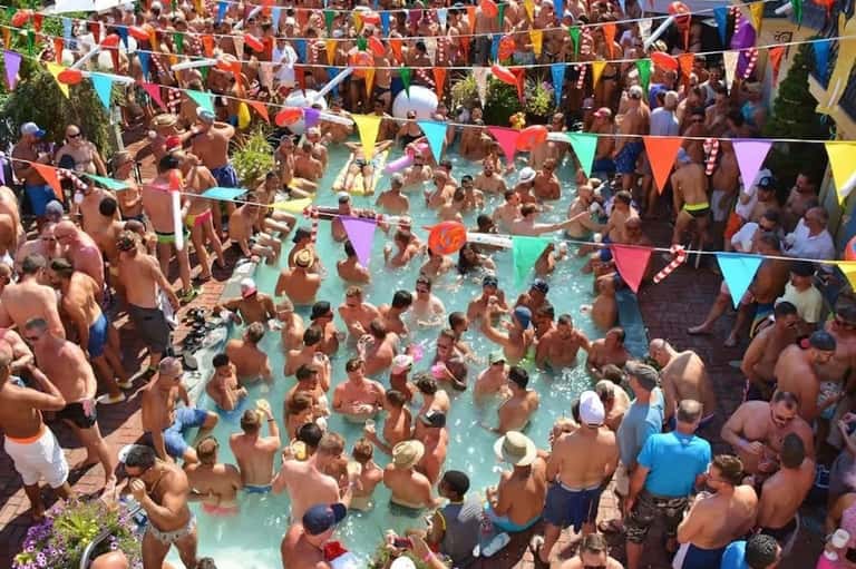 Crowded pool party with colorful bunting decorations and many guests swimming and socializing