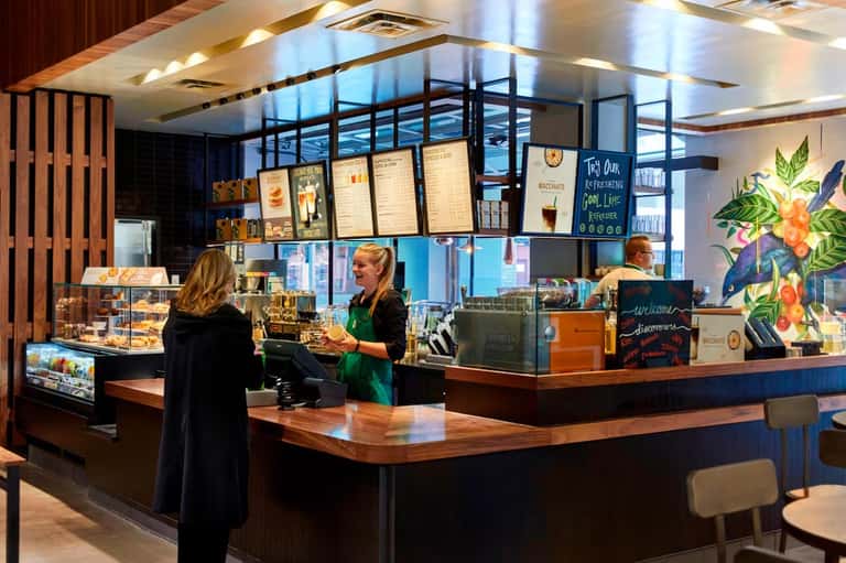 Contemporary coffee shop interior with modern counter, menu boards, barista staff, and bright lighting