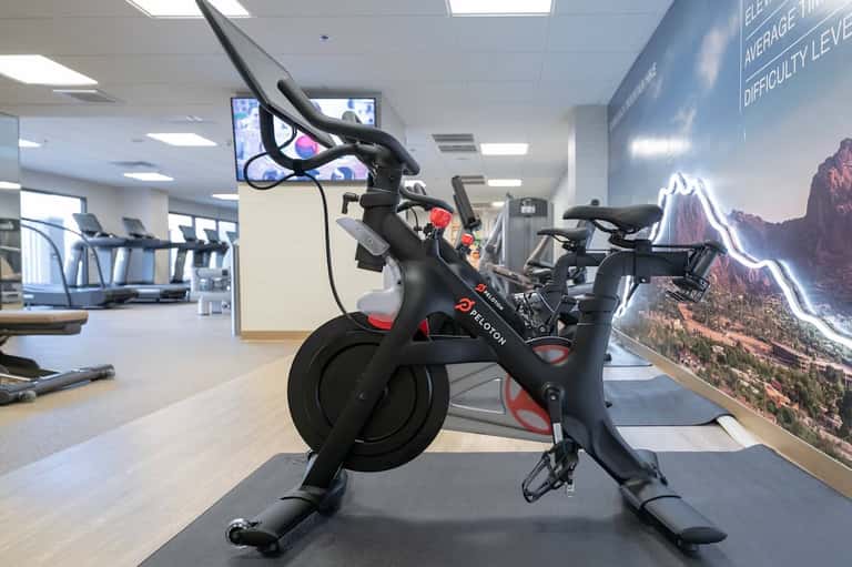 Peloton stationary bike in bright fitness studio with mountain landscape mural
