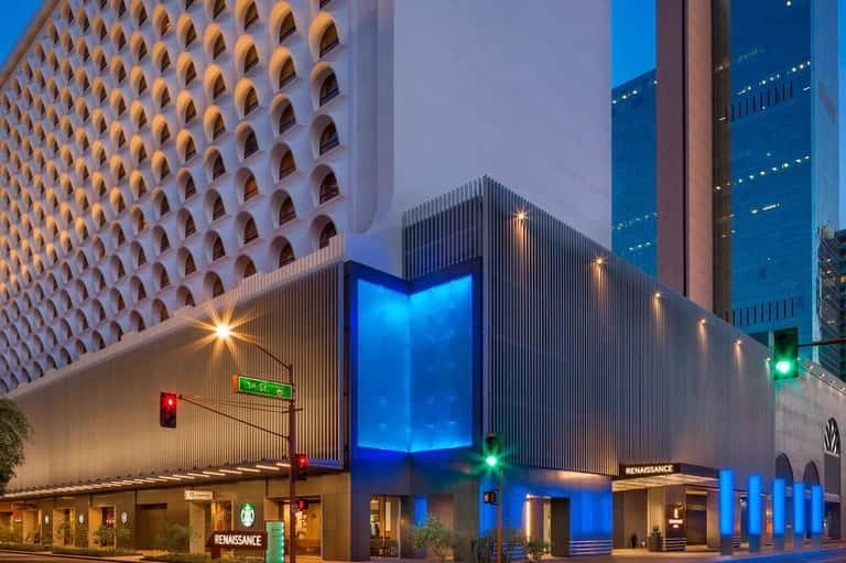 Contemporary hotel building at night with illuminated blue entrance and geometric patterned white facade