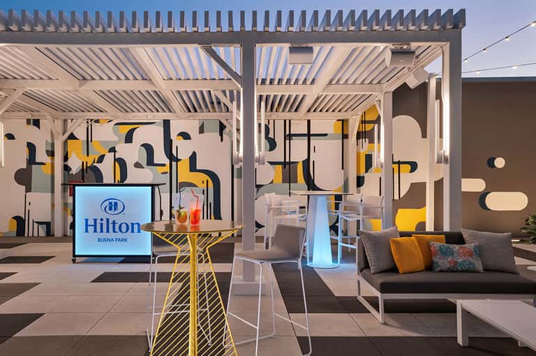 Contemporary outdoor patio with geometric wall art, pergola, and lounge seating