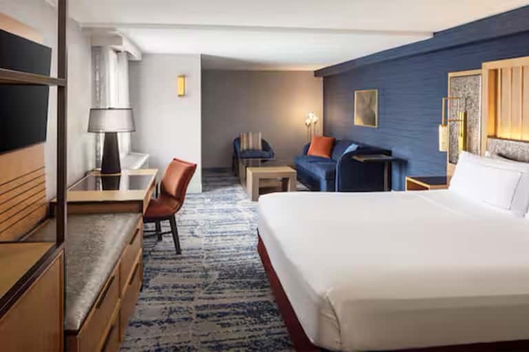 Hotel room with king bed, blue accent wall, sitting area, and modern furnishings