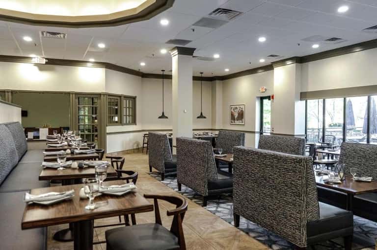 Fine dining restaurant interior with booth seating, pendant lighting, and lake view windows