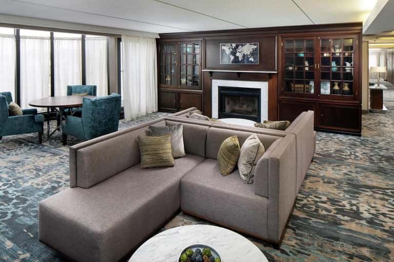 Luxury suite living room with gray sectional sofa, fireplace, wood cabinetry, and elegant furnishings