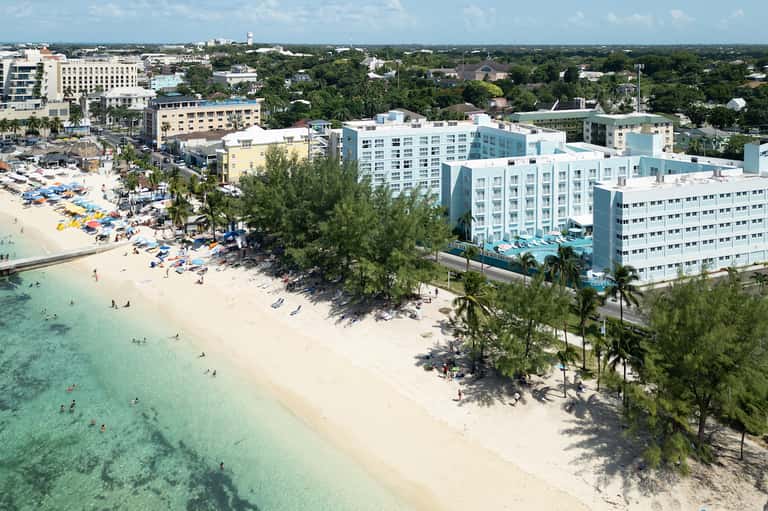 Aerial view of beachfront resort with turquoise water, white sand beach, and palm trees