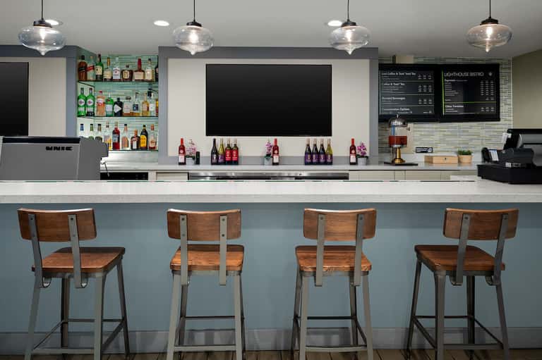 Modern bar interior with wooden stools, liquor bottles, and menu boards