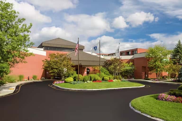 Modern red brick resort building with manicured landscaping and circular driveway