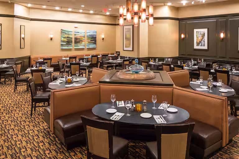 Upscale dining room with booth seating, round tables, and modern lighting fixtures