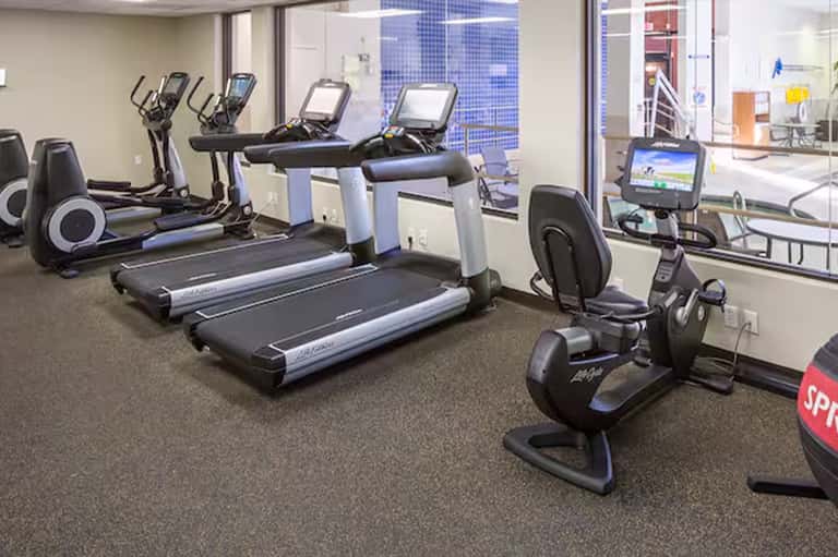 Modern fitness center with treadmills, elliptical machines, and exercise bikes with floor-to-ceiling windows