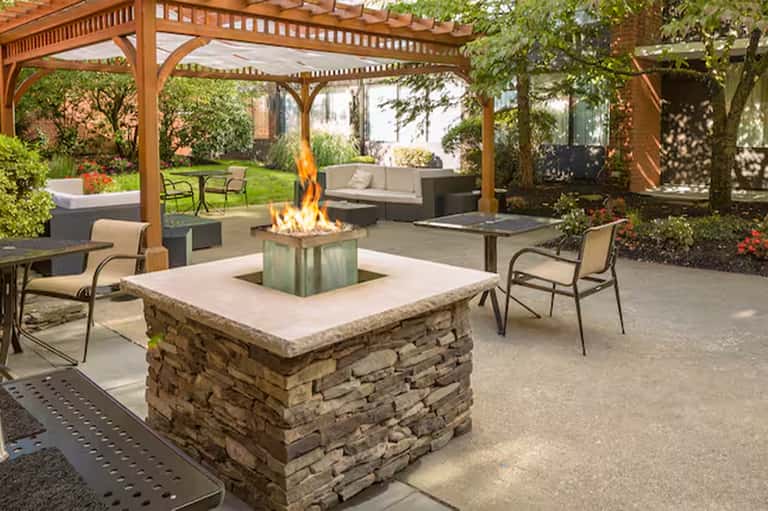 Outdoor patio with stone fire pit, wooden pergola, and lounge seating