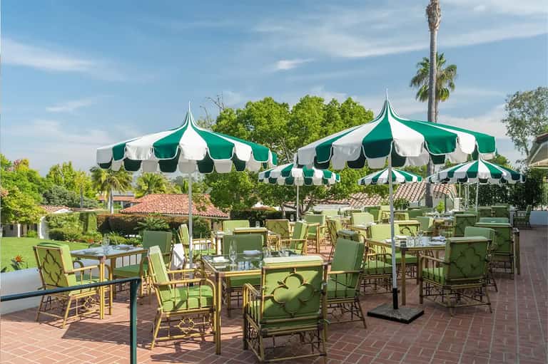 Outdoor patio dining area with green and white striped umbrellas and elegant seating
