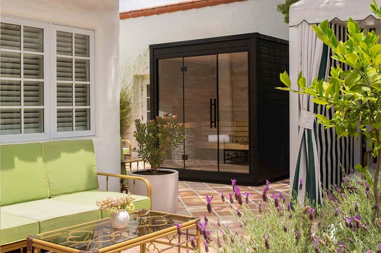 Contemporary patio with lime green lounge seating, black-framed glass doors, and purple flowering plants