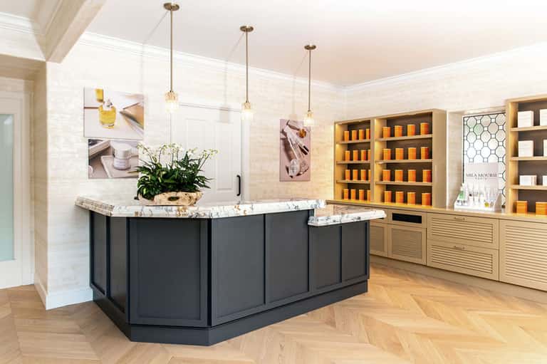 Spa reception area with marble counters, golden product displays, and modern pendant lighting
