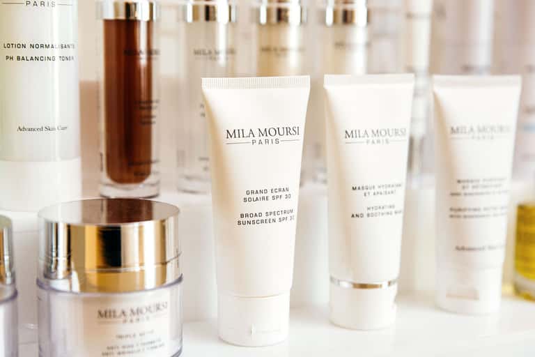Luxury skincare products displayed including Mila Moursi Paris serums, creams, and sunscreen bottles