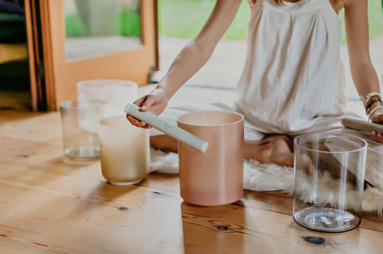 Woman's hands lighting a candle on wooden table with glass cups and minimal decor
