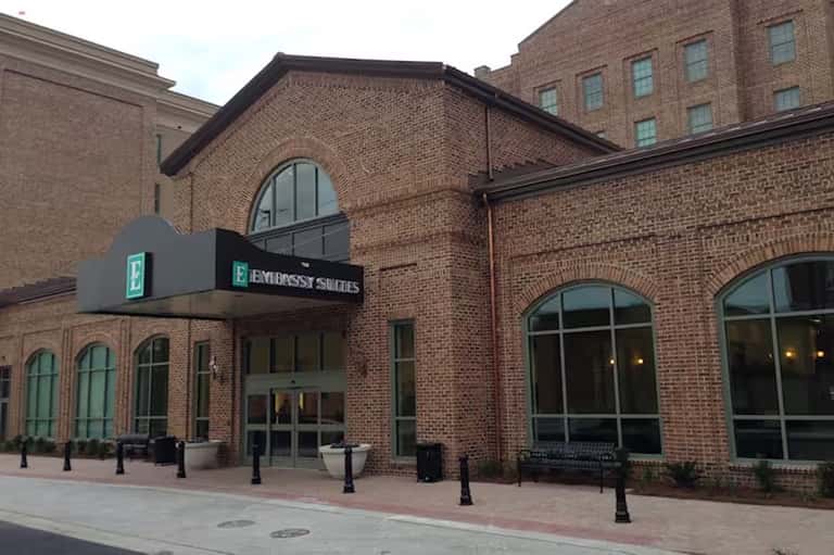 Embassy Suites hotel brick exterior with arched windows and entrance sign on brick plaza