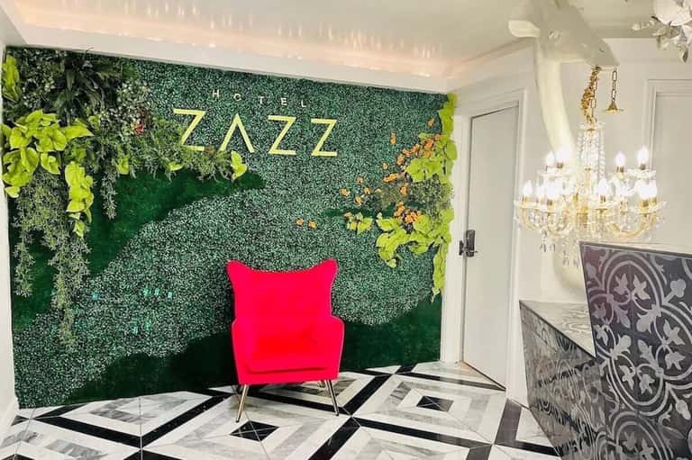 Elegant hotel lobby with living green wall, gold signage, and crystal chandelier
